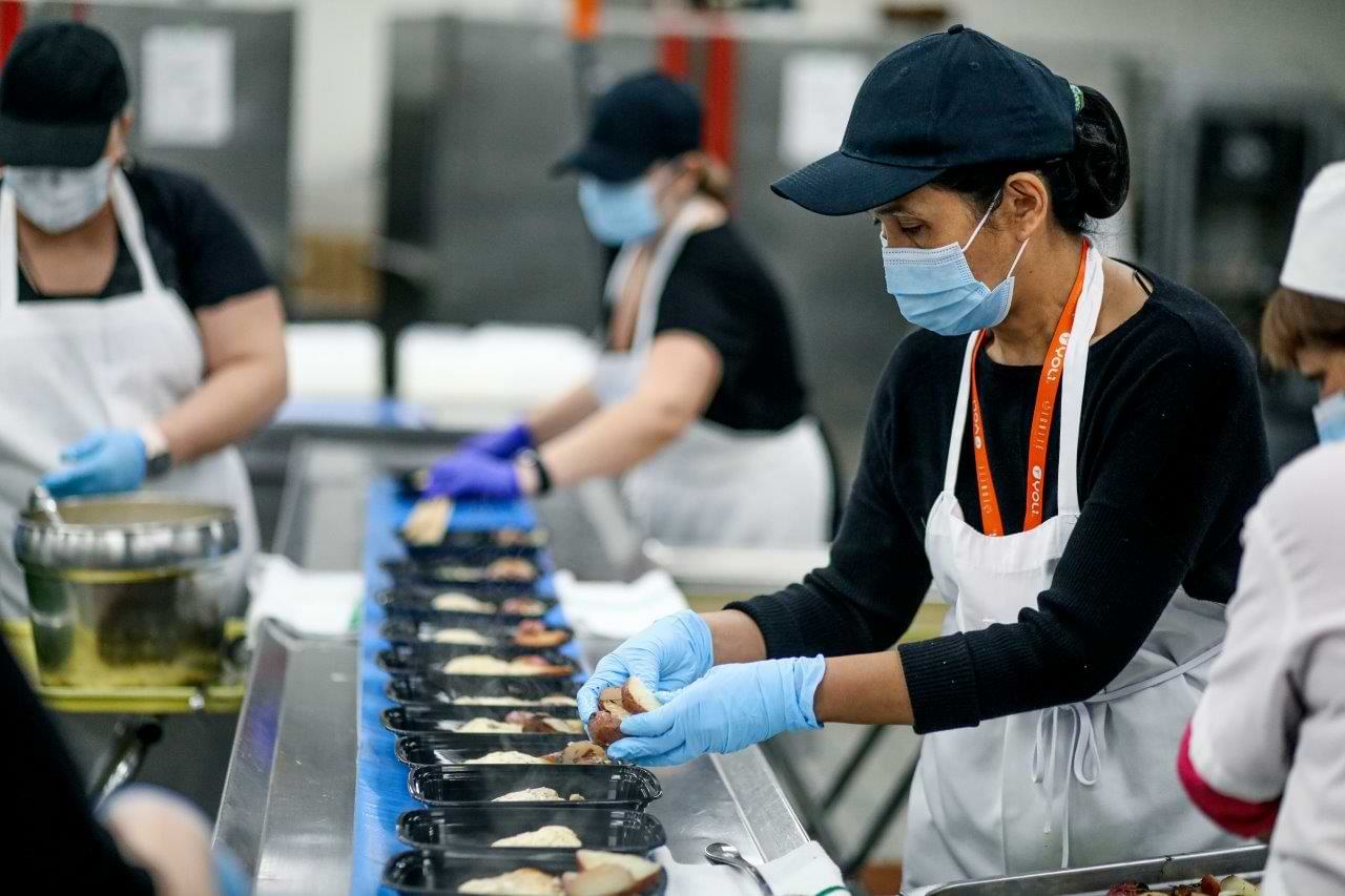 Centerplate staff place potatoes into a meal container